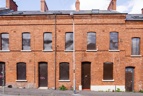 фотографія Row of unoccupied terraced houses boarded up with metal sheets to stop vandalism