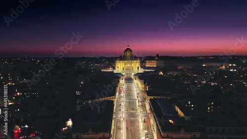 aerial view of rome saint peter basilica vatican city illuminated at night,drone moving out the window flying over conciliazione street at dusk photo