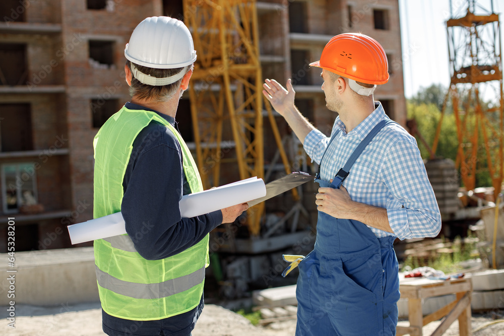 Two men engineers at a construction site are looking at the drawings Two men engineers at a construction site are looking at the drawings