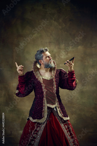 Canvas Print Royal person, man in female dress taking on mobile phone against vintage green background