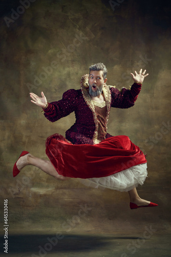 Photography Gray-haired royal person, monarch in female attire, dress and shoes jumping against dark green background