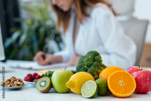 Beautiful smart nutritionist woman working with computer while taking notes in the nutritionist consultation photo