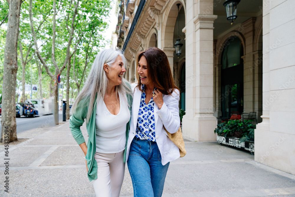 Beautiful senior women meeting outdoors in the city - Two mature female adults friends bonding and having fun while shopping outdoors