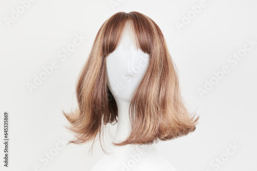 Natural looking dark brunet wig on white mannequin head. Middle length brown hair on the plastic wig holder isolated on white background, front view . photo