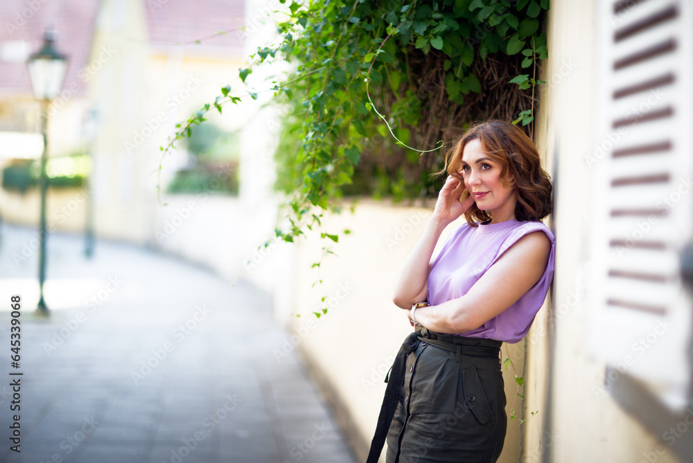 Fototapeta premium Beautiful successful middle aged woman posing on the street of the old city