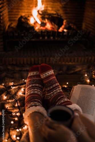 Crop legs with book near fireplace