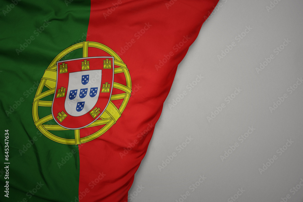 big waving national colorful flag of portugal on the gray background.