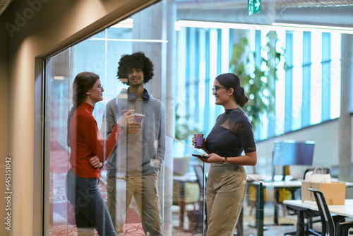 Amidst the modern glass walls of a startup office, a diverse group of colleagues, including an African American man, engage in a coffee-fueled discussion, exemplifying collaboration and innovation in