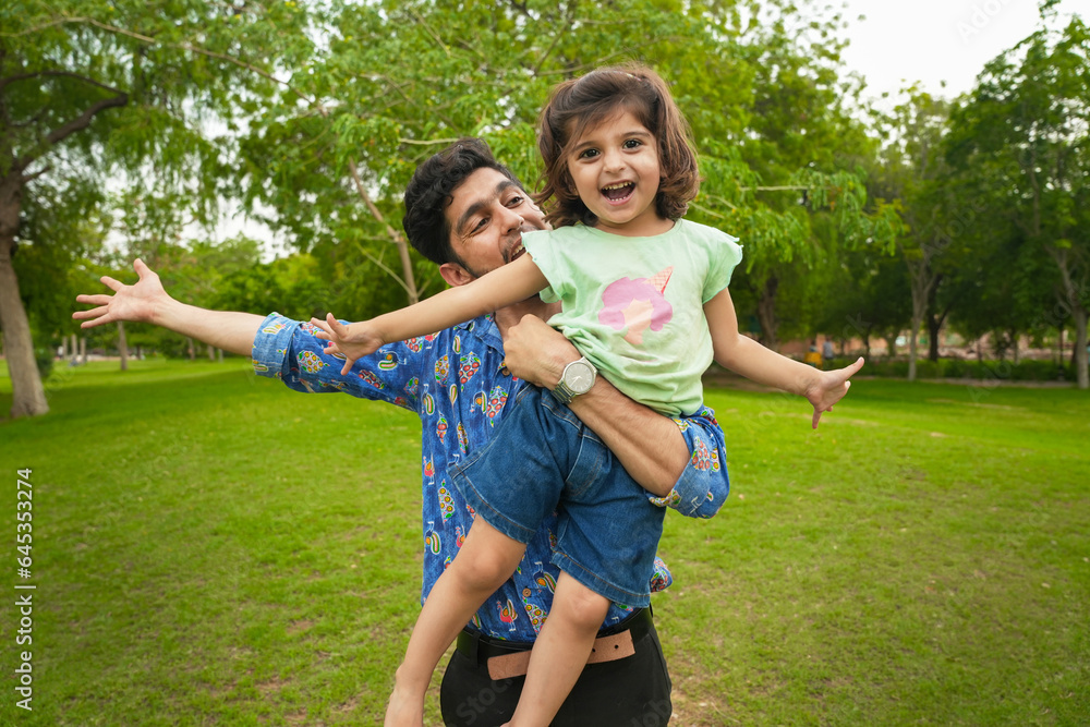 Fototapeta premium Happy carefree young indian father and child daughter playing at summer park.Family and fatherhood concept.