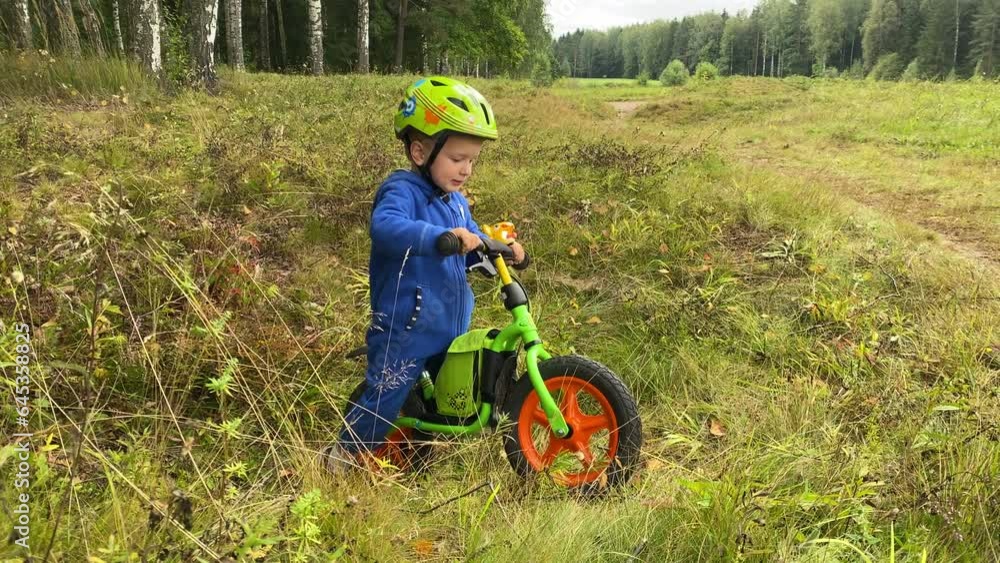 toddler child in safety helmet with balance bike in summer forest, little boy trying to get out of the pit on bike toddler child in safety helmet with balance bike in summer forest, little boy trying to get out of the pit on bike