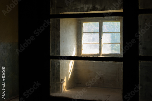 Sunlight entering a dark spooky room through filthy windows in an abandoned house