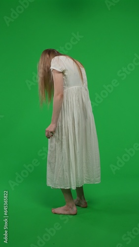 Full-size half turn vertical green screen, chroma key shot of a posessed female, woman figure, ghost, poltergeist, zombie shot from behind. Ominious, hunched figure. photo