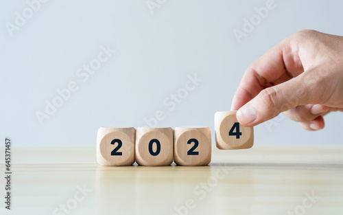 Happy New Year 2024 concept. Hand holding number 2024 on wooden cube blocks. preparation for new year change and start of the new year for life, business, plan, goals, target, and strategy concept
