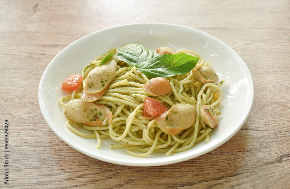 pesto spicy stir fried spaghetti with slice sausage and basil sauce on plate 