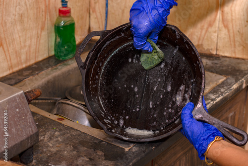 Woman's hands to cleaning cast iron pan with dish washer and scrubber. photo