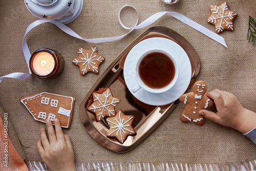 Kid takes Christmas gingerbread cookies. Atmospheric festive Christmas decorations with hot cocoa. Home coziness and warmth concept. © Natalia
