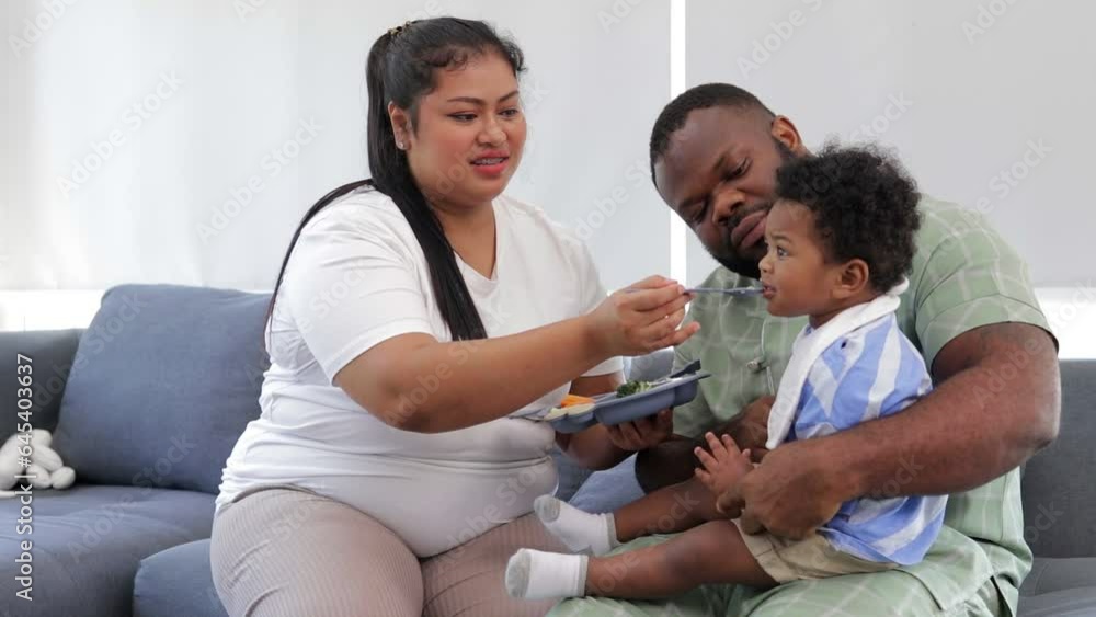 Mixed race little boy happily eating food fed by mother. Mixed race family concept. baby growth. African American Mixed race little boy happily eating food fed by mother. Mixed race family concept. baby growth. African American