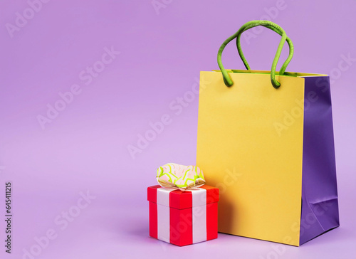 Present and shopping bag near placard pastel background