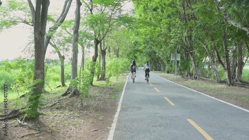 Wallpaper Mural Both of young women in sportswear riding a bicycle in the park, Carry a backpack with a solar panel to charge smartphone. Torontodigital.ca