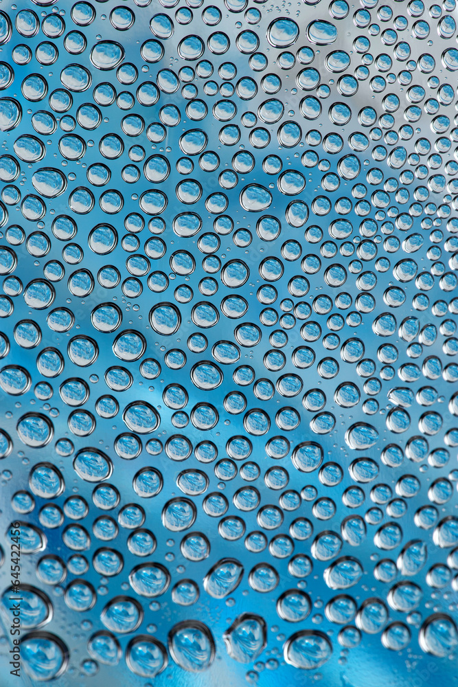 water drops on the transparent surface of a glass bottle on a blue background, condensation