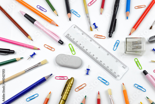 Bright set for school, stationery on a white background. Colored pencils, pens, plastic paints and paper clips, flat layers with space for text.