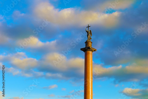 Alexander Column near the Winter Palace in Saint Petersburg, Russia. A monument with a sculpture of an Angel holding a cross against a blue sky with clouds