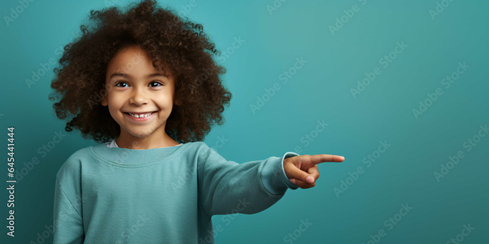a child pointing to a plain blue background, happiness, joy, fashion - obrazy, fototapety, plakaty 