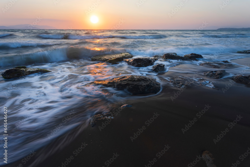 A seascape photographed with a long exposure technique at sunset.