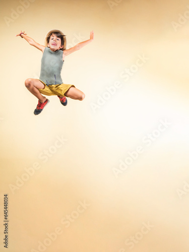 Boy with a straw hat jumping as high as he can.