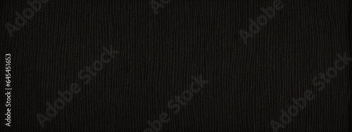 Panoramic close-up texture of natural weave cloth in dark and black color. Fabric texture of natural cotton or linen textile material. Black fabric wide background.