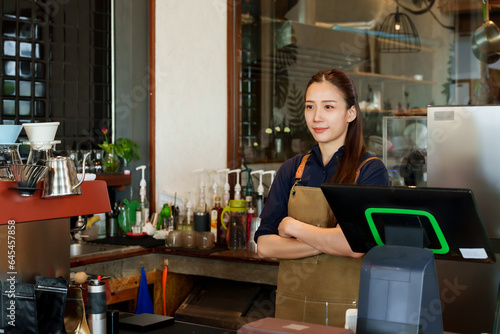 Beautiful Asian women, they stand with their arms crossed smiling behind the counter. to take pictures to promote a coffee shop that is a minimalist style shop that is his small business
