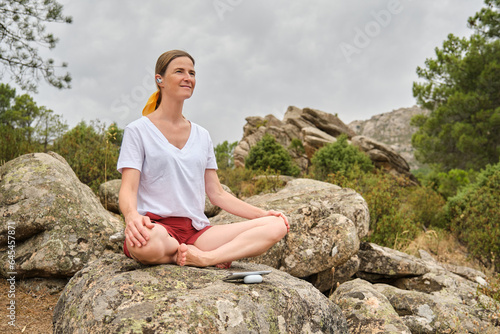 Woman meditating in easy pose while sitting on rock