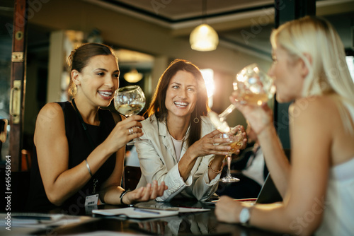 Diverse group of female business friends having a glass of wine after work in a bar photo