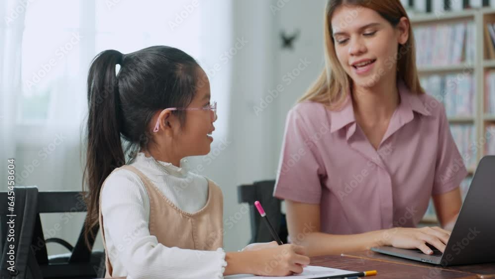 Young women elementary teacher using laptop and teaching lesson to little girl pupil in classroom at school. Back to school concept, Education and learning concept Young women elementary teacher using laptop and teaching lesson to little girl pupil in classroom at school. Back to school concept, Education and learning concept
