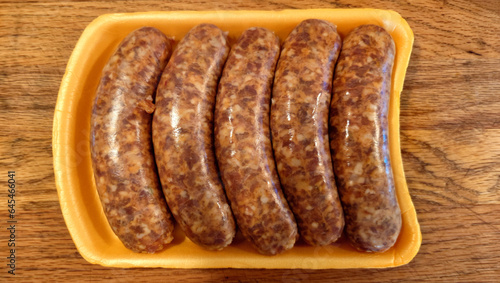 Five links of uncooked Italian sausage in plastic packaging tray