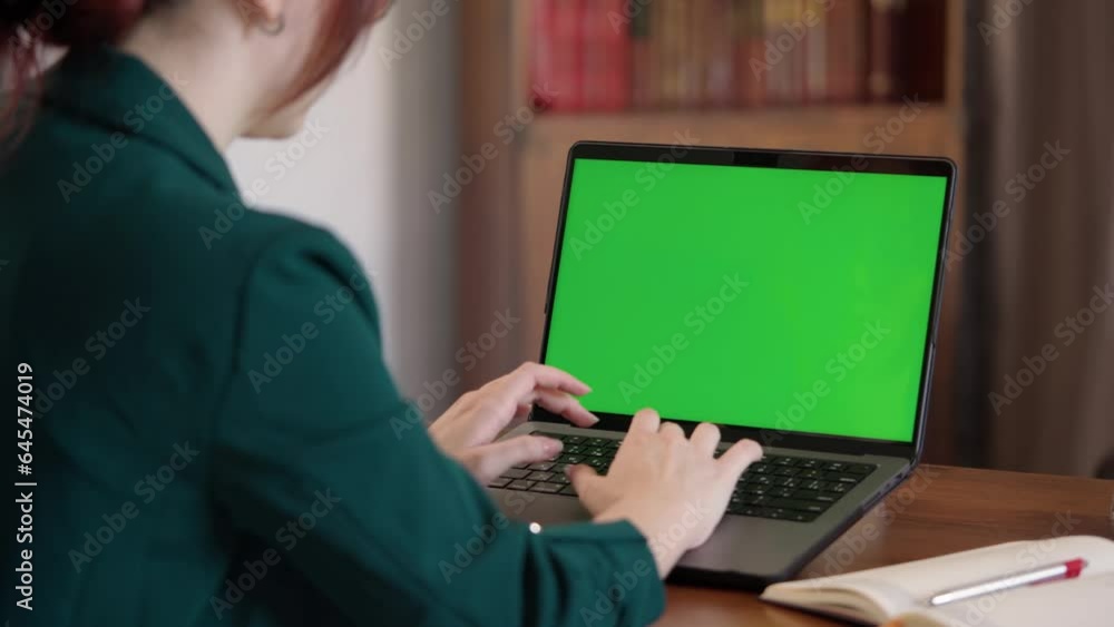 Girl Typing on Keyboard Of Laptop with Green Mock-up Screen. Female Student Learning Online in Cozy Room- Library Girl Typing on Keyboard Of Laptop with Green Mock-up Screen. Female Student Learning Online in Cozy Room- Library