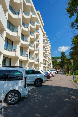 the street of the resort town on the seashore, the facade of a multi-storey house hotel and parked cars, background of travel during vacation