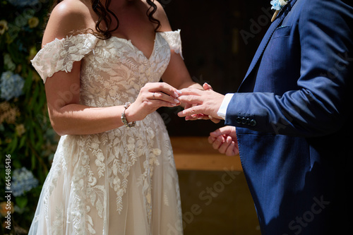 Anonymous bride and groom exchanging rings during wedding photo