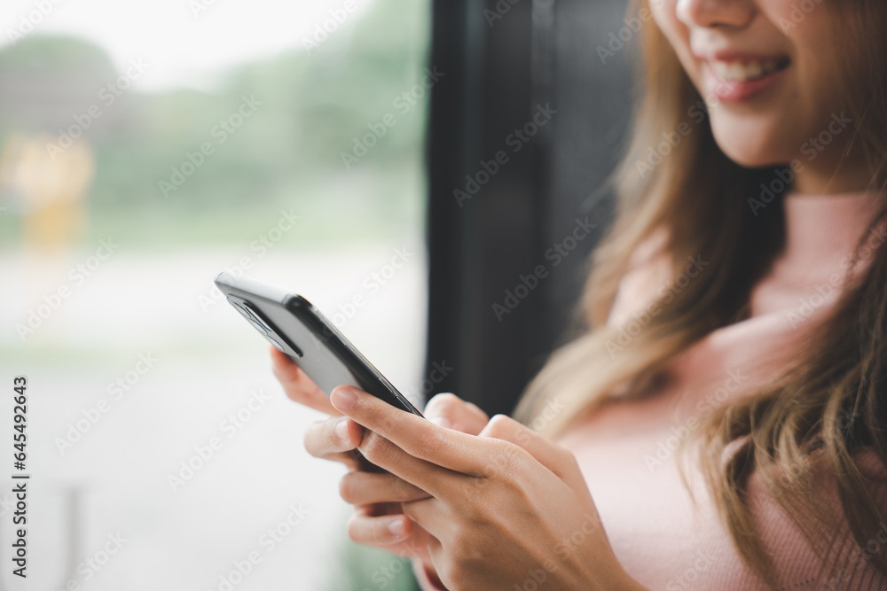 Young woman typing text message on smart phone device apps in cafe, beautiful female holding cellphone in hands and chatting social network with friends or reading email, mobile phone