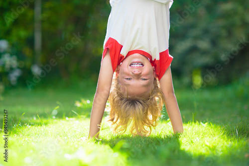 Foto Little boy hanging upside down. Handstand exercise