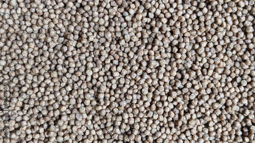 Brown color fish pellets, fish feed texture background, top view shot Brown color fish pellets, fish feed texture background, top view shot