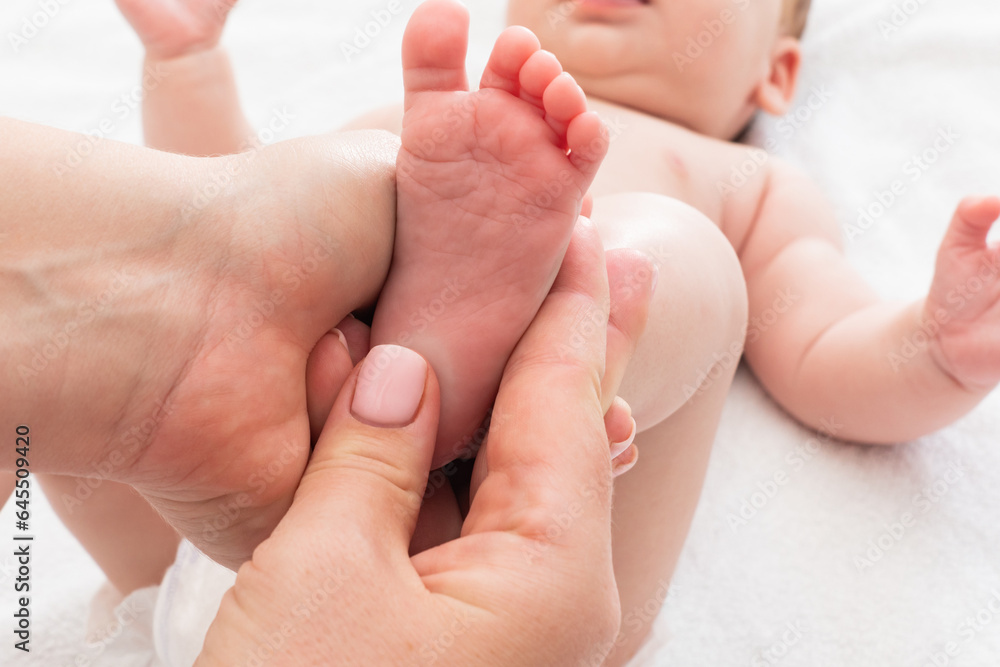 Mother's hands work on infant's feet, Concept of early baby massage benefits Mother's hands work on infant's feet, Concept of early baby massage benefits