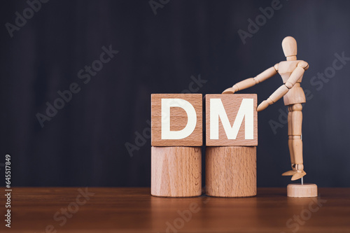 There is wood cube with the word DM. It is an abbreviation for Direct message as eye-catching image.