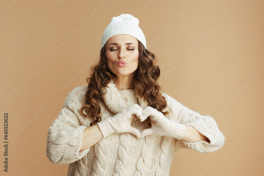 stylish woman showing heart shaped hands on beige background