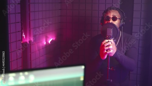 cool black guy is singing romantic song in musical recording studio, portrait in isolation booth photo