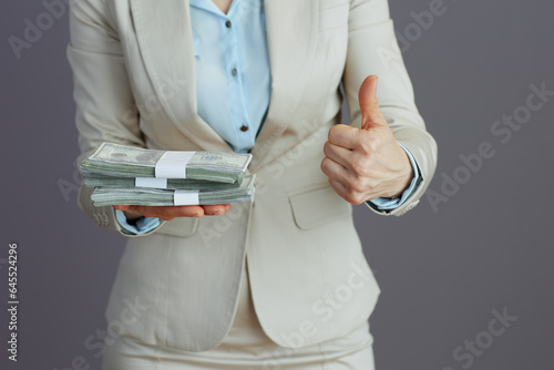 Business owner woman in light business suit showing thumbs up