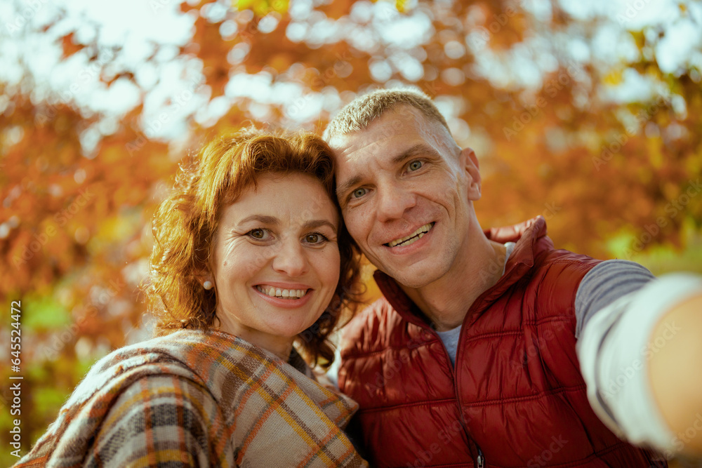 Fototapeta premium smiling stylish boyfriend and girlfriend in park taking selfie