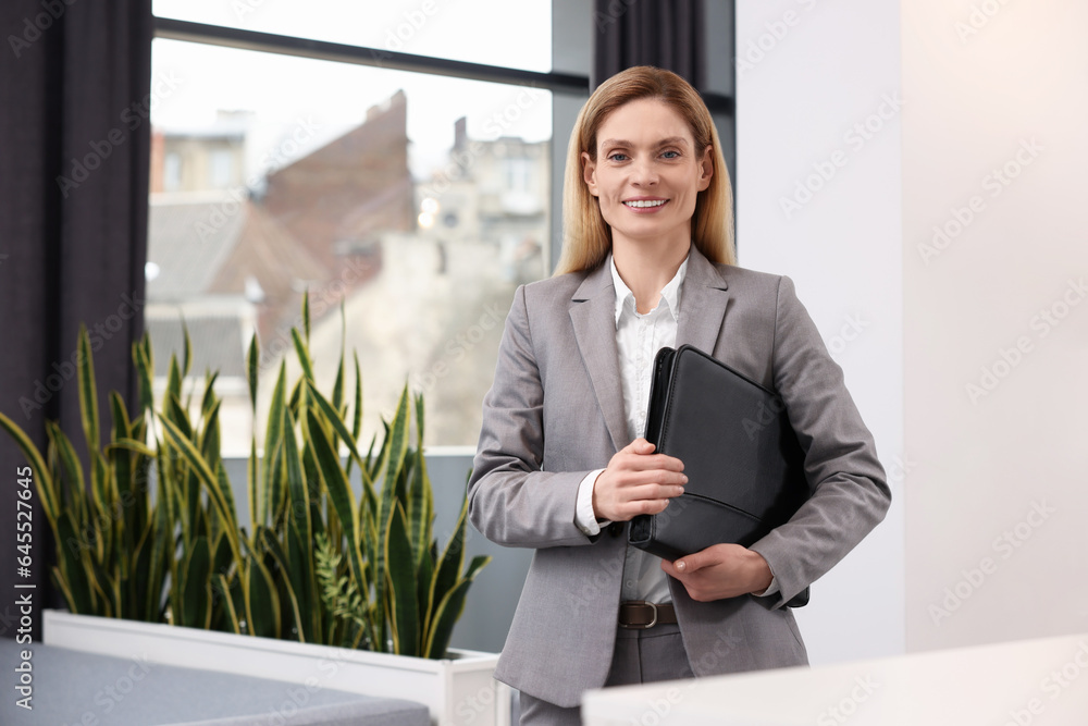 Happy real estate agent with leather portfolio indoors Happy real estate agent with leather portfolio indoors