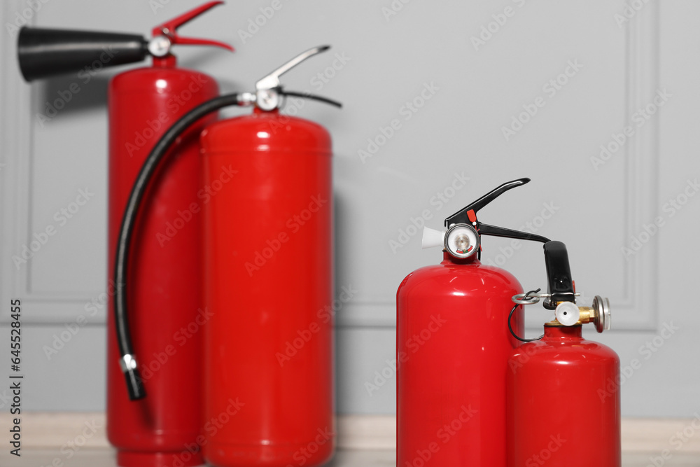 Obraz premium Red fire extinguishers near grey wall, selective focus