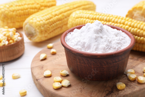 Bowl with corn starch and kernels on white table, closeup